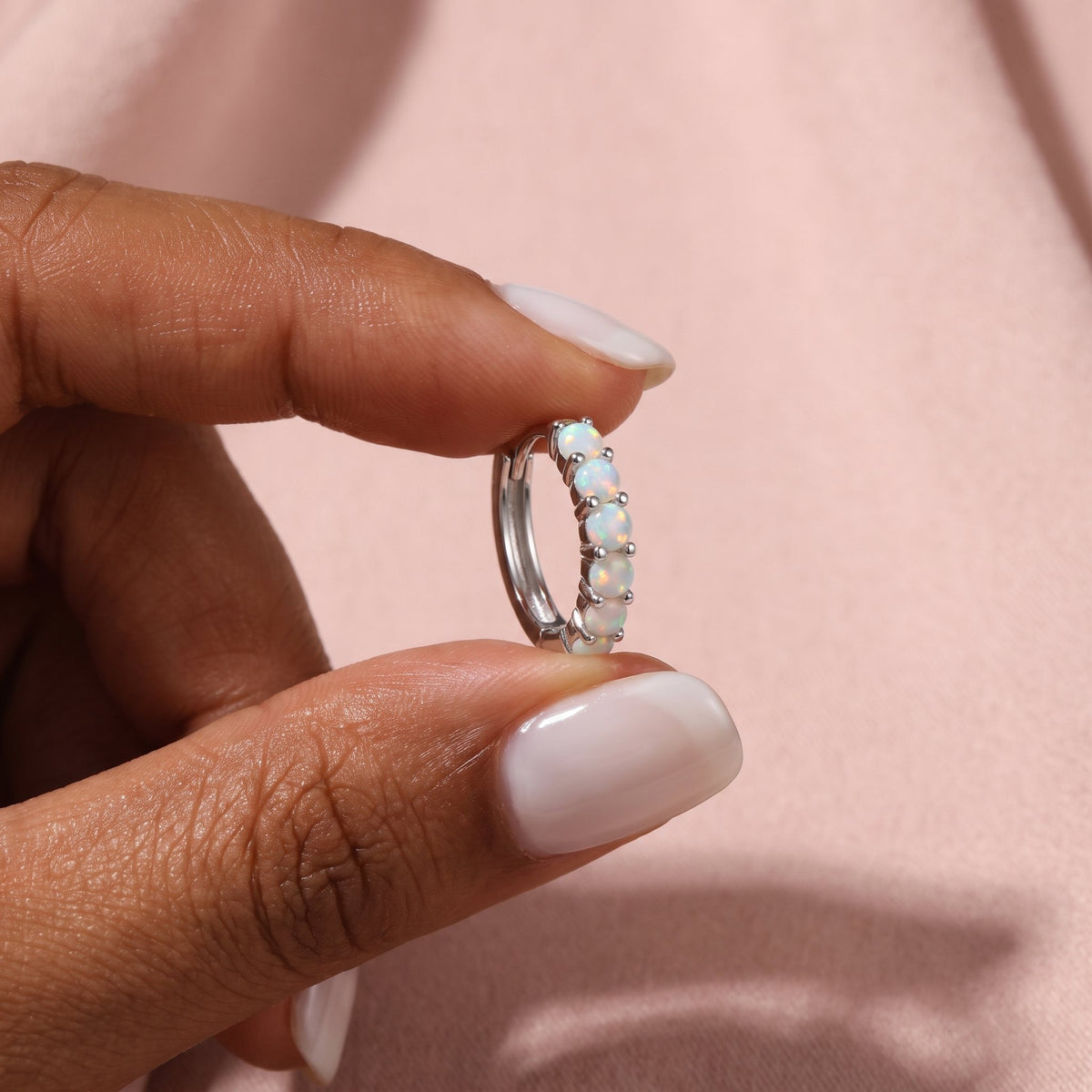 Fingers holding a moonstone hoop earring